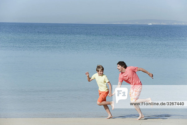 Spanien  Mallorca  Vater und Sohn (8-9) beim Laufen über den Strand