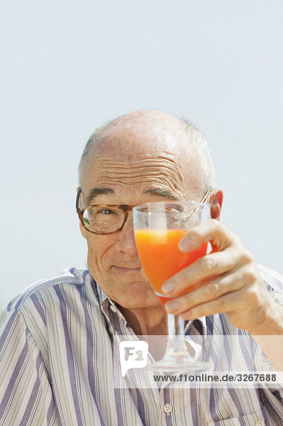 Spain  Mallorca  Senior man holding glass with orange juice  portrait