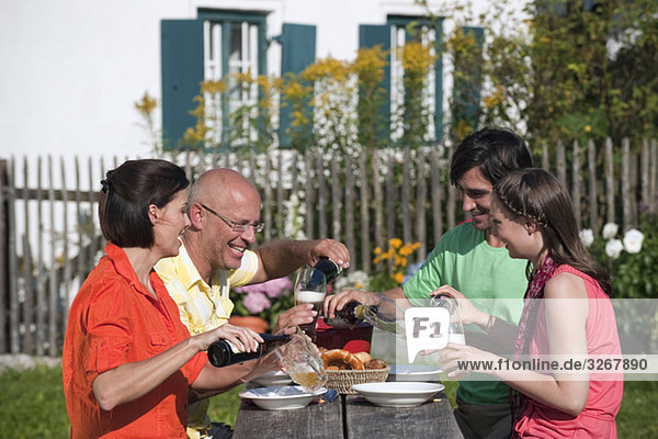 Deutschland  Bayern  Vier Personen trinken Bier im Garten  lächelnd  Portrait