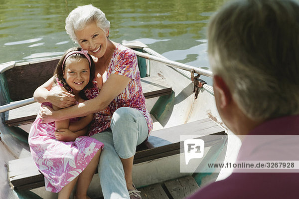 Italy  South Tyrol  Grandparents and granddaughter (8-9) sitting in rowing boat  smiling  portrait