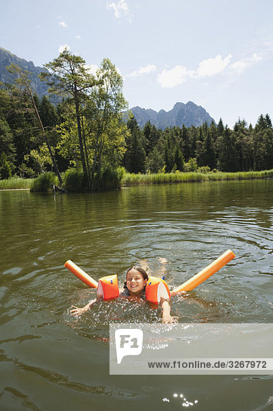 Italien,  Südtirol,  Mädchen (8-9) im See schwimmend,  lächelnd,  Portrait