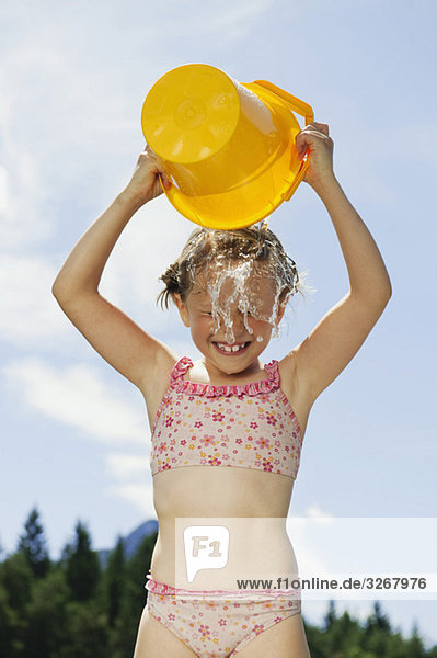 Italien  Südtirol  Mädchen (6-7) gießt einen Eimer Wasser über den Kopf