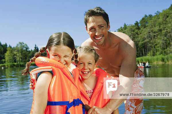 Italy  South Tyrol  Father and daughters (6-7) (8-9)  daughters wearing life jackets  smiling  portrait