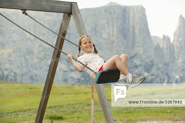 Italy  Seiseralm  Girl (6-7) sitting on swing  portrait
