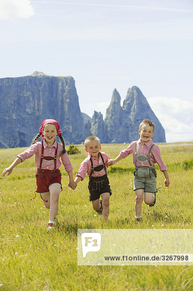 Italy  Seiseralm  Three children (4-5)  (6-7)  (8-9) running in field