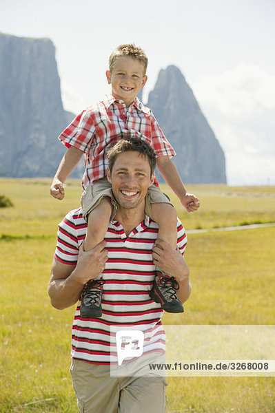 Italien  Seiseralm  Fahter trägt Sohn (6-7) auf der Schulter  lächelnd  Portrait