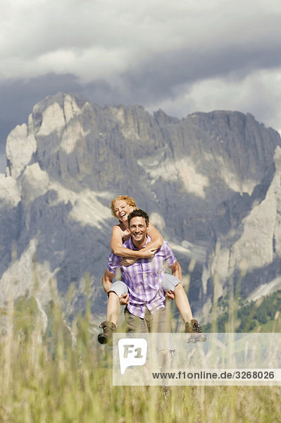 Italy  Seiseralm  Man carrying woman on back  laughing  portrait