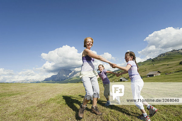 Italy  Seiseralm  Mother and daughter (6-9) playing in meadow  smiling