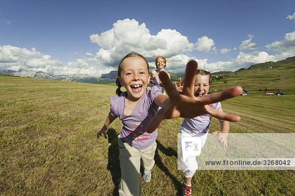 Italy  Seiseralm  Mother and daughter (6-9) running in meadow  laughing  portrait