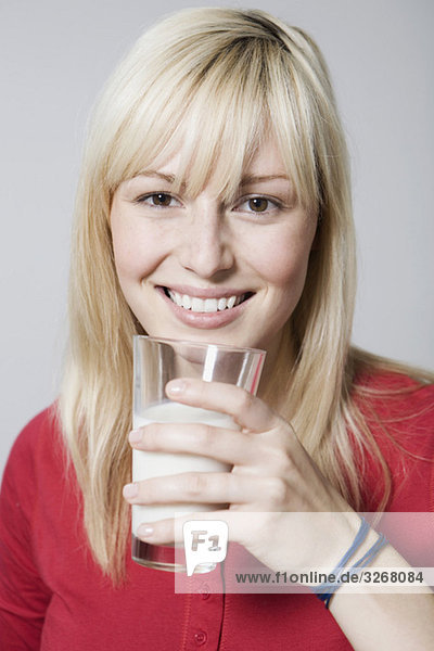 Young woman holding glass of milk  smiling  close-up