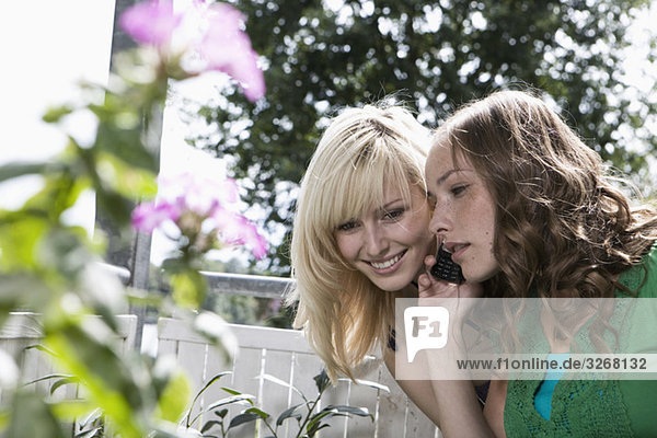 Young women on balcony using mobile phone  (differential focus)