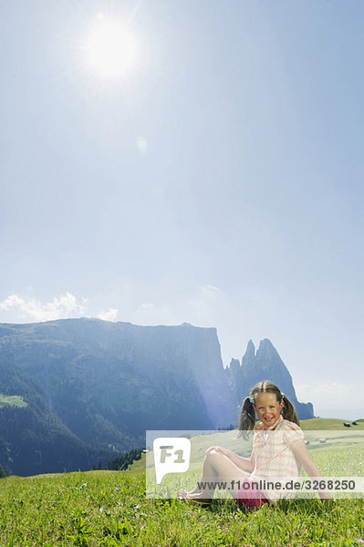 Italien  Südtirol  Seiseralm  Mädchen (6-7) sitzend auf der Wiese