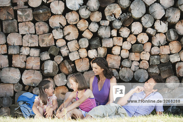 Italien  Südtirol  Familie ruht vor Holzhaufen