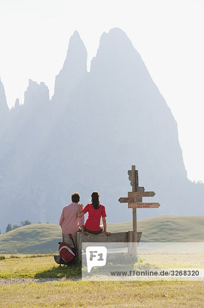 Italien  Südtirol  Seiseralm  Paar auf Bank sitzend  Rückansicht