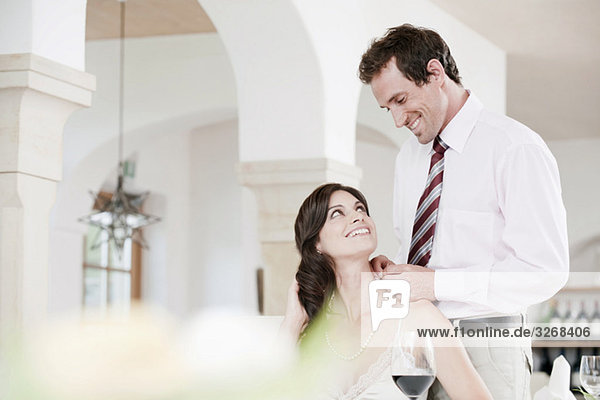 Couple in restaurant  man placing necklace on woman