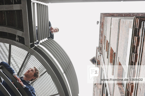 Deutschland,  Hamburg,  Zwei Geschäftsleute auf der Plattform des Bürogebäudes mit Blick nach unten,  Portrait,  Tiefblick