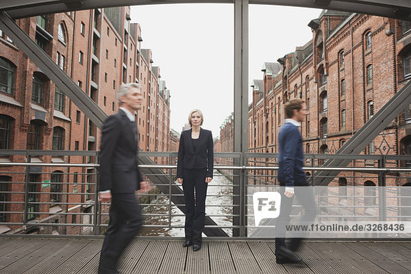 Two Businessmen crossing bridge  Businesswoman in background