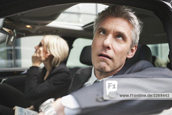 Germany  Hamburg  Two Business people sitting in car  Businessman looking up  portrait  close-up