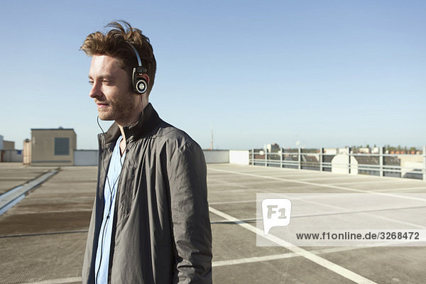 Young man on empty parking level wearing headphones listening to music