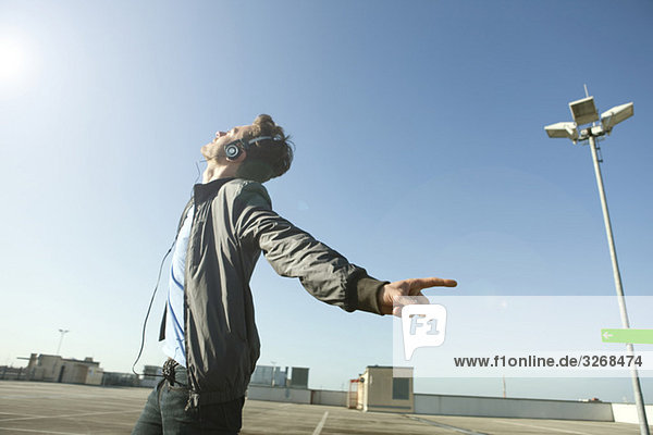 Young man on deserted parking level wearing headphones listening to music