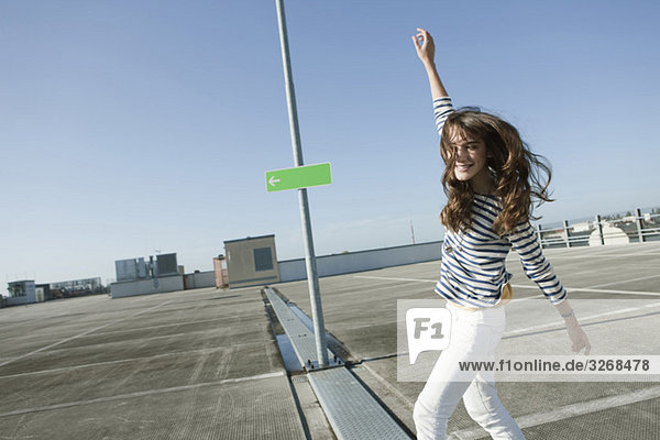 Junge Frau auf verlassenem Parkplatz tanzend  lächelnd  Portrait