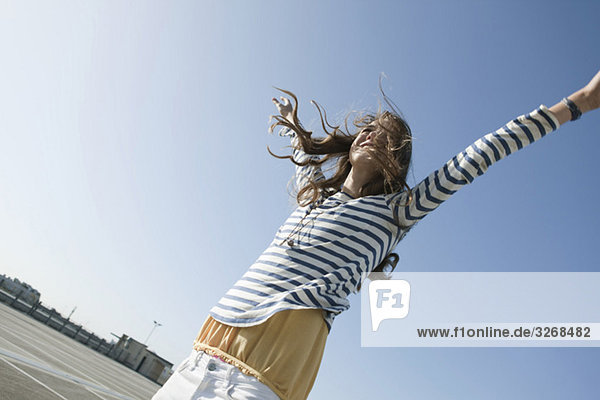 Young woman on parking level  raising arms  smiling  portrait
