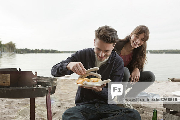 Germany  Berlin  Lake Wannsee  Young couple having a barbecue