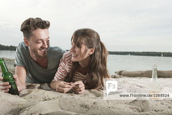 Germany  Berlin  Lake Wannsee  Young couple lying on beach  smiling  portrait