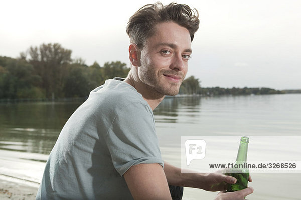Lake Wannsee  Young man holding bottle  smiling  portrait
