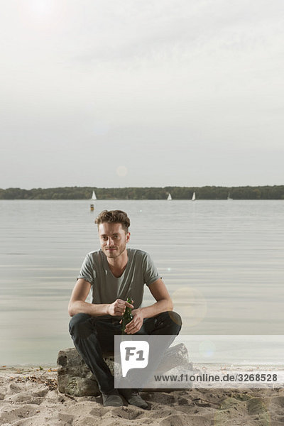 Young man sitting on rock near lake  portrait