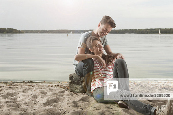 Germany  Berlin  Lake Wannsee  Young couple sitting on lakeshore  portrait
