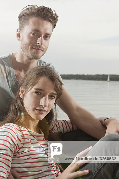 Germany  Berlin  Lake Wannsee  Young couple sitting on lakeshore  portrait