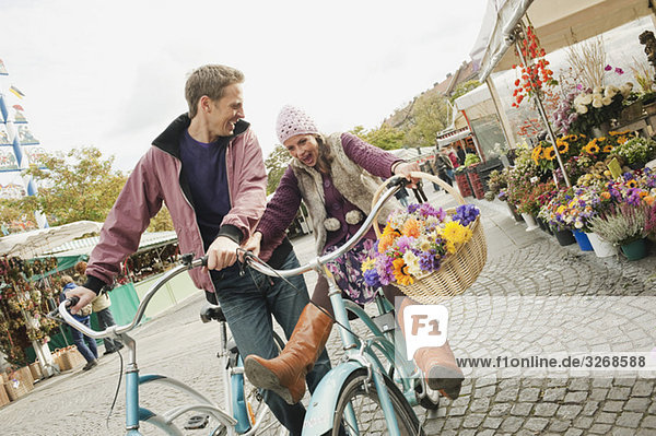 Germany  Bavaria  Munich  Viktualienmarkt  Couple with bicycles  laughing  portrait