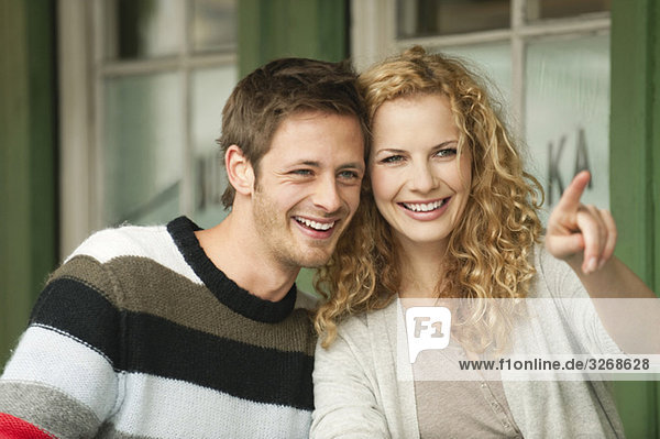 Junges Paar am Viktualienmarkt  Frau zeigt  lächelnd  Porträt