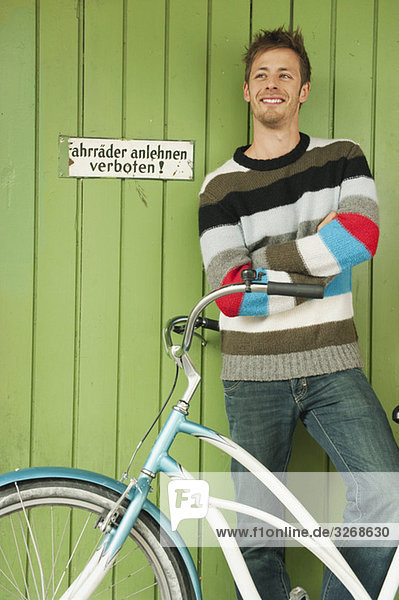 Mann mit Fahrrad vor dem Tor stehend  lächelnd  Portrait