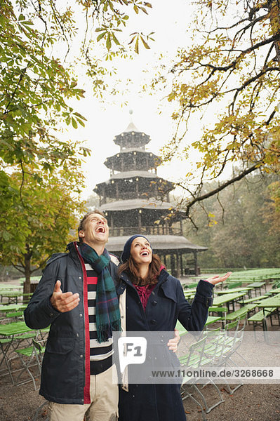 Germany  Bavaria  Munich  English Garden  Couple in rainy beer garden  Chinese tower in background  portrait
