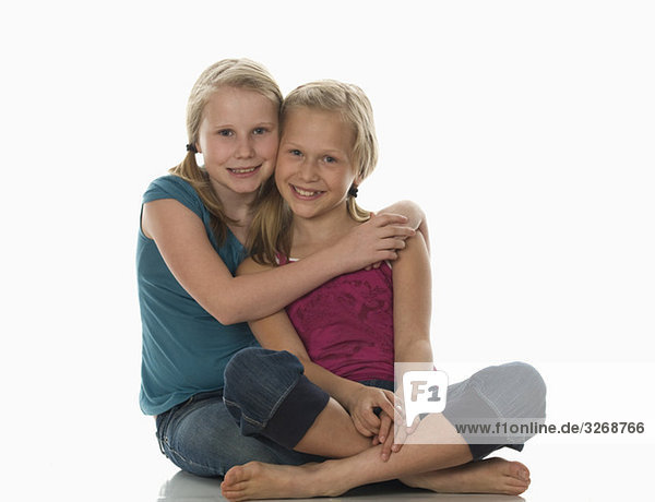 Zwei Mädchen (10-11) umarmend  lächelnd  porträtierend