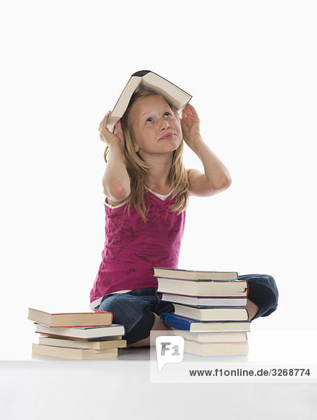 Portrait eines Mädchens (10-11) mit gestapelten Büchern  ein Buch auf dem Kopf