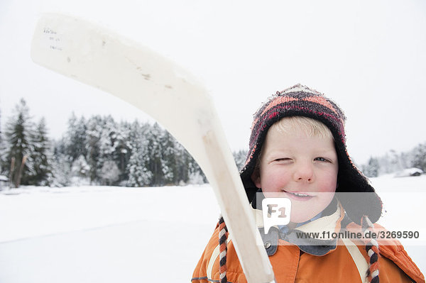 Italy South Tyrol Seiseralm Boy (4-5) holding hockey stick portrait close-up