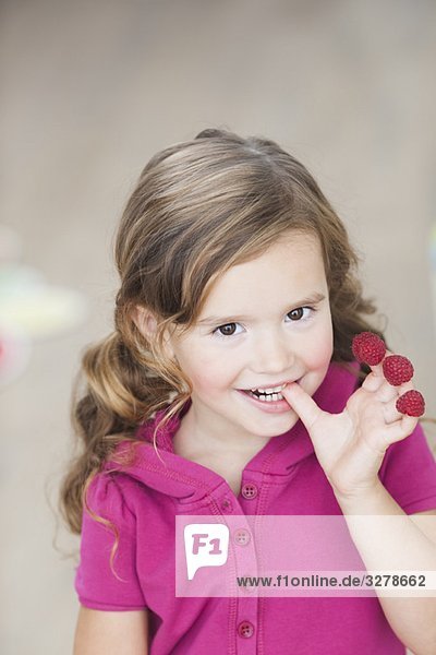 young girl eating berries from fingers