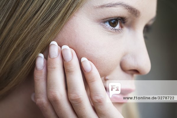 Junge Frau ruht mit dem Kopf auf der Hand