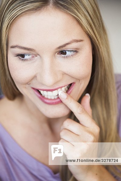 Junge Frau zeigt auf ihre Zähne