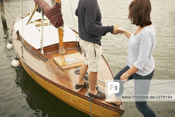 Man helping woman onto old boat