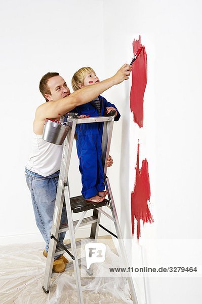 Mann und Kleinkind Junge malen Wand rot