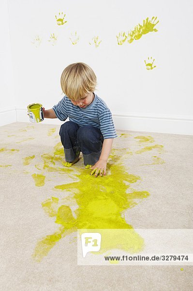 Junge schwappt Farbe auf den Teppich