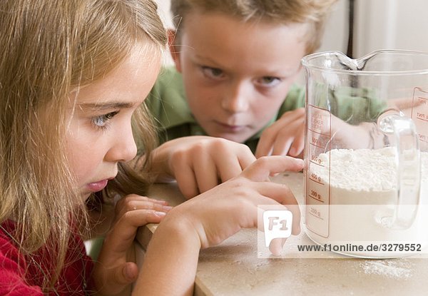 Mädchen und Junge messen Mehl