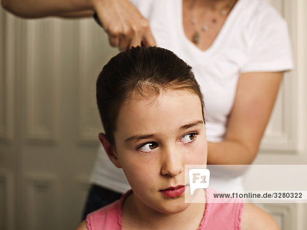 A woman tying a girls hair back