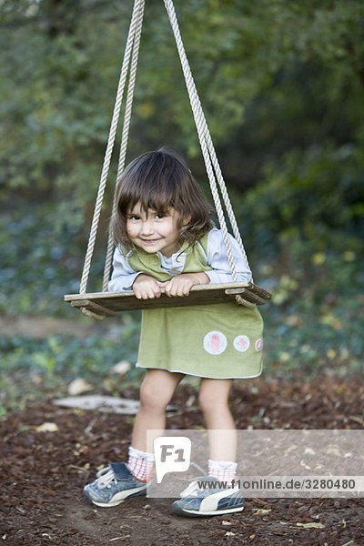 Kleines Mädchen spielt auf Holzschaukel