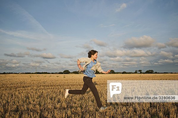Ein junges Mädchen  das durch ein Feld rennt.