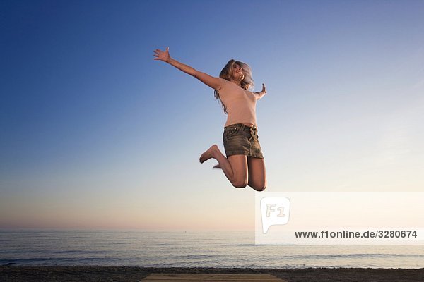 Frau am Strand springt vor Freude